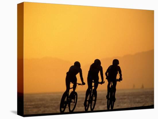 Silhouette of Three Men Riding on the Beach-Mitch Diamond-Stretched Canvas