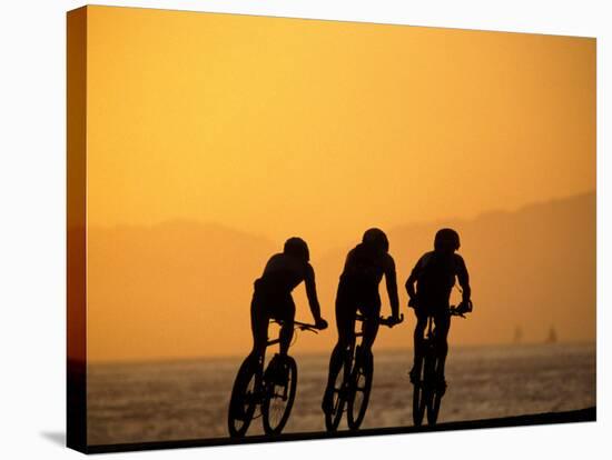 Silhouette of Three Men Riding on the Beach-Mitch Diamond-Stretched Canvas