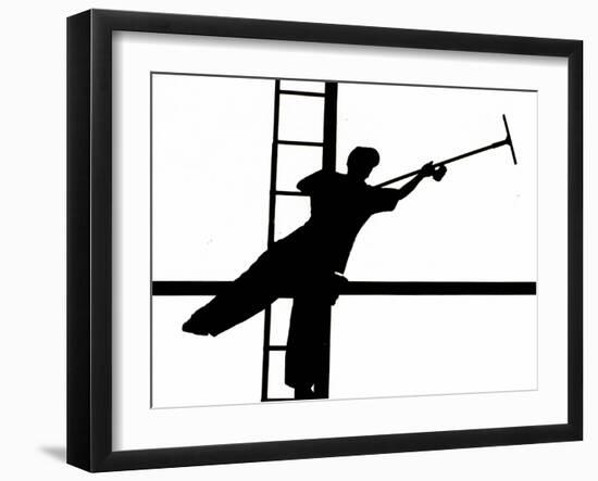 Silhouetted against the Bright Morning Sun, a Window Cleaner Stretches to Clean a Spot-null-Framed Photographic Print