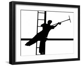 Silhouetted against the Bright Morning Sun, a Window Cleaner Stretches to Clean a Spot-null-Framed Photographic Print