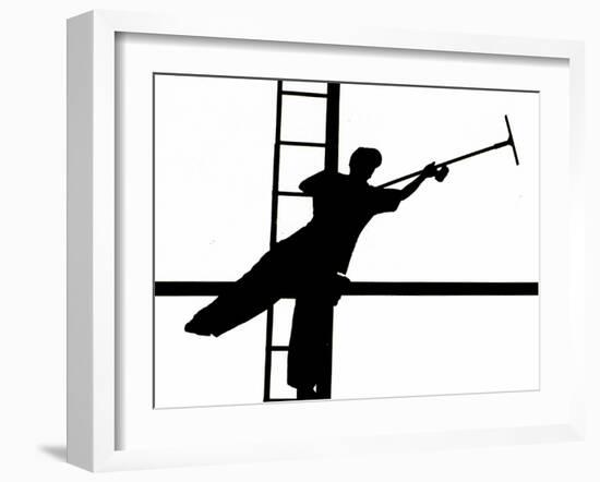 Silhouetted against the Bright Morning Sun, a Window Cleaner Stretches to Clean a Spot-null-Framed Photographic Print