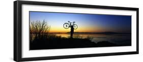 Silhouetted Cyclist Holding Bicycle over Head, River's Edge, Sunset, Alaska-null-Framed Photographic Print