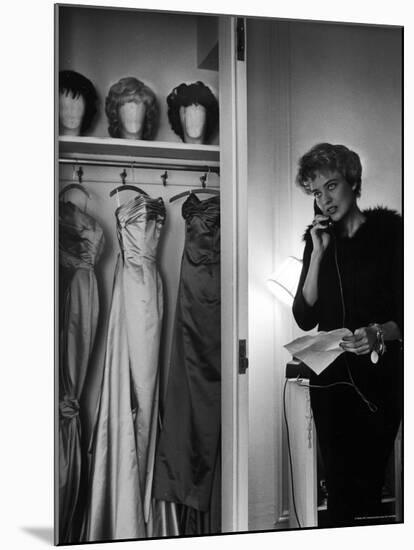 Singer Julie Wilson on Phone Beside Closet with Hanging Evening Dresses and Wigs on Top Shelf-Nina Leen-Mounted Premium Photographic Print