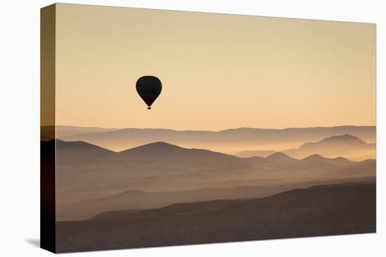 Single Hot Air Balloon over a Misty Dawn Sky, Cappadocia, Anatolia, Turkey, Asia Minor, Eurasia-David Clapp-Stretched Canvas