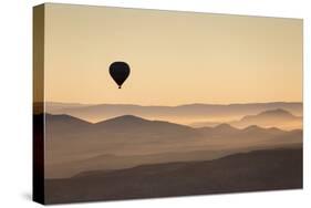 Single Hot Air Balloon over a Misty Dawn Sky, Cappadocia, Anatolia, Turkey, Asia Minor, Eurasia-David Clapp-Stretched Canvas