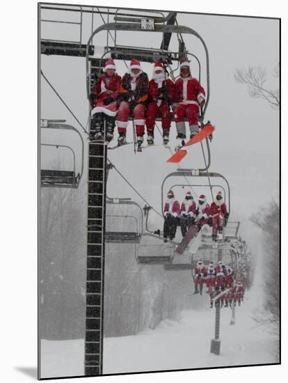 Skiers and Snowboarders Dressed as Santa Claus Ride up the Ski Lift-null-Mounted Photographic Print