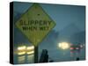 Slippery When Wet Sign in Fore with Traffic in Background in Rain on California Highway 14-Ralph Crane-Stretched Canvas