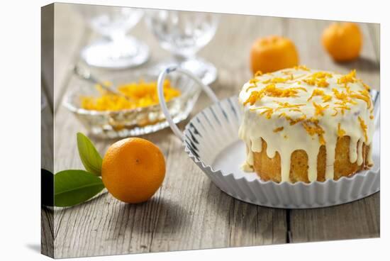 Small Orange Cake with White Icing on Wooden Table-Jana Ihle-Stretched Canvas