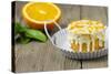 Small Orange Cake with White Icing on Wooden Table-Jana Ihle-Stretched Canvas