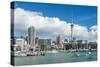 Small sailboats cruise in Auckland harbour in front of the city skyline, Auckland, New Zealand-Logan Brown-Stretched Canvas