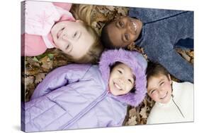 Smiling Children Lying on Autumn Leaves-Ian Boddy-Stretched Canvas