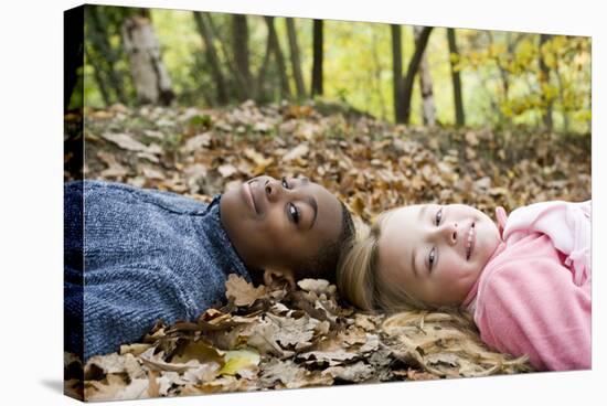 Smiling Children Lying on Autumn Leaves-Ian Boddy-Stretched Canvas