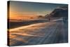 Snow Blows across an Icelandic Road at Sunrise with Mountains Looming in the Distance-Alex Saberi-Stretched Canvas