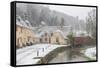 Snow covered houses by By Brook in Castle Combe with a dog enjoying a paddle, Wiltshire, England, U-Paul Porter-Framed Stretched Canvas