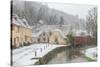 Snow covered houses by By Brook in Castle Combe with a dog enjoying a paddle, Wiltshire, England, U-Paul Porter-Stretched Canvas