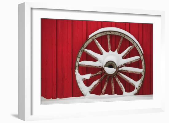 Snow-covered wagon wheels against red barn near town of Banff, Canadian Rockies, Alberta, Canada-Stuart Westmorland-Framed Photographic Print