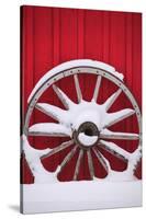 Snow-covered wagon wheels against red barn near town of Banff, Canadian Rockies, Alberta, Canada-Stuart Westmorland-Stretched Canvas