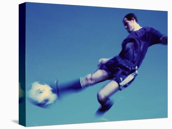 Soccer Player Jumping in Mid Air to Kick a Soccer Ball-null-Stretched Canvas