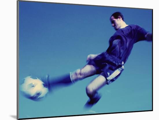 Soccer Player Jumping in Mid Air to Kick a Soccer Ball-null-Mounted Photographic Print