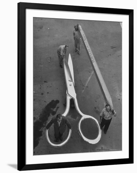 Stagehands Pushing a Pair of Gigantic Scissors on a Dollie Next to Two Men Carrying a 21 Ft. Pencil-Allan Grant-Framed Photographic Print