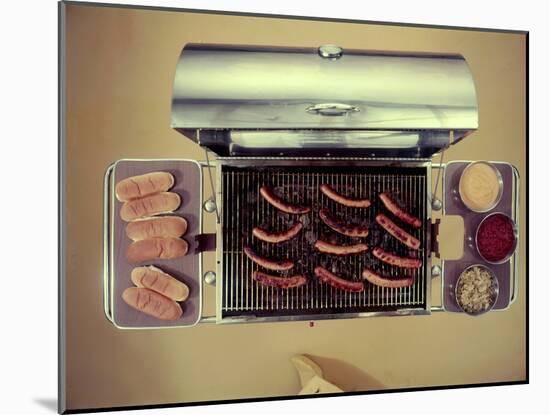 Stainless Steel Barbecue Grill, Upon Which are Buns, Hot Dogs, and Condiments, 1960-Eliot Elisofon-Mounted Photographic Print