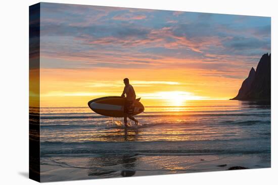 Stand up paddle boarder man admiring midnight sun walking back to the beach-Roberto Moiola-Stretched Canvas