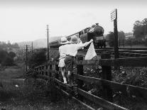 Two Children Stand on a Fence and Wave a Handkerchief at a Passing Steam Train-Staniland Pugh-Photographic Print
