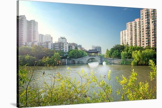 Stone bridge with pagoda style roofing, flanked by old style apartment buildings on the left and ne-Andreas Brandl-Stretched Canvas