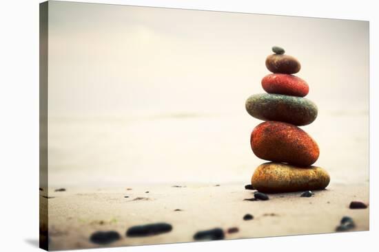 Stones Pyramid on Sand Symbolizing Zen, Harmony, Balance. Ocean in the Background-Michal Bednarek-Stretched Canvas