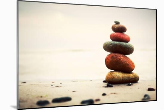 Stones Pyramid on Sand Symbolizing Zen, Harmony, Balance. Ocean in the Background-Michal Bednarek-Mounted Photographic Print