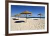 Straw umbrellas on empty white sand beach with clear sea behind, Ilha do Farol, Culatra Barrier Isl-Stuart Black-Framed Photographic Print