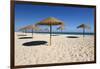 Straw umbrellas on empty white sand beach with clear sea behind, Ilha do Farol, Culatra Barrier Isl-Stuart Black-Framed Photographic Print