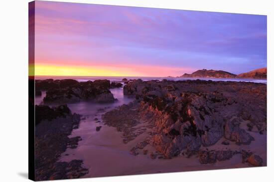 Sunrise Casts a Red Pink Hue on Rocks of a Beach Looking Towards Nugget Point-Eleanor-Stretched Canvas