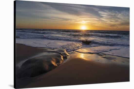 Sunset reflecting off the water on the sand of a beach-Sheila Haddad-Stretched Canvas