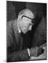 Swiss Architect Le Corbusier Leaning Down to Write with His Glasses Pushed Back on His Forehead-null-Mounted Premium Photographic Print