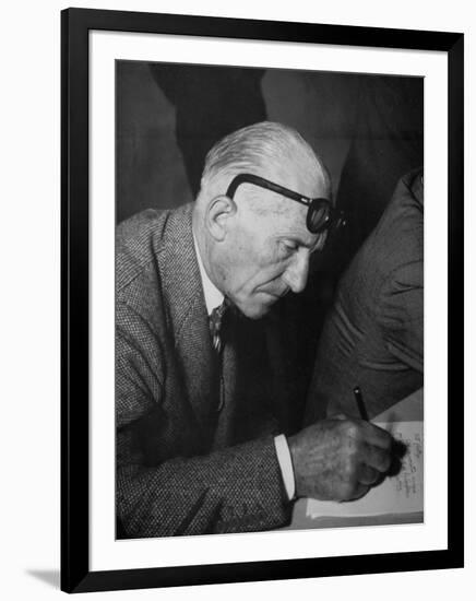 Swiss Architect Le Corbusier Leaning Down to Write with His Glasses Pushed Back on His Forehead-null-Framed Photographic Print