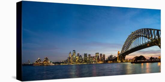 Sydney's iconic buildings lit up as dusk settles over the city, Sydney, New South Wales, Australia-Logan Brown-Stretched Canvas