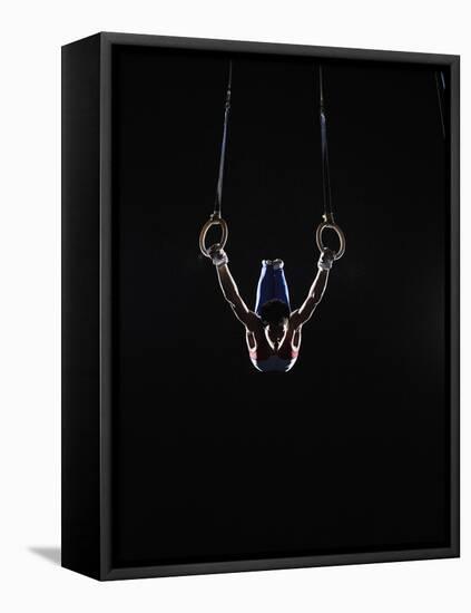 Teenage (16-17) Male Gymnast Practicing on Rings against Black Background-Thomas Barwick-Framed Stretched Canvas