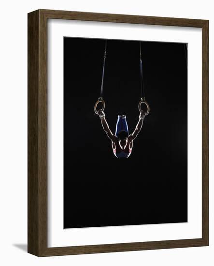 Teenage (16-17) Male Gymnast Practicing on Rings against Black Background-Thomas Barwick-Framed Photographic Print