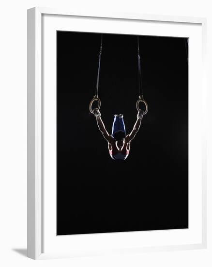 Teenage (16-17) Male Gymnast Practicing on Rings against Black Background-Thomas Barwick-Framed Photographic Print