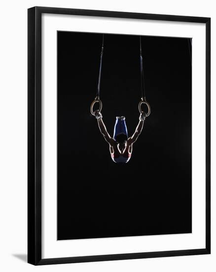 Teenage (16-17) Male Gymnast Practicing on Rings against Black Background-Thomas Barwick-Framed Photographic Print