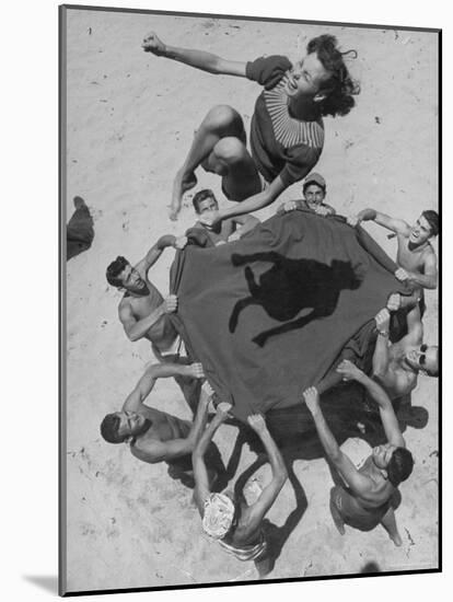 Teenaged Boys Using Blanket to Toss Their Friend, Norma Baker, Into the Air on the Beach-John Florea-Mounted Photographic Print