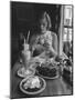 Teenaged Girl Sitting in Drugstore Eating a Hamburger-Hank Walker-Mounted Photographic Print