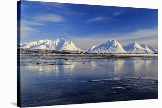 The blue sky and snow capped mountains are reflected in the frozen water  Breivikeidet Lyngen Alps -ClickAlps-Stretched Canvas