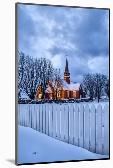 The illuminated church at dusk in the cold snowy landscape at Flakstad Lofoten Norway Europe-ClickAlps-Mounted Photographic Print