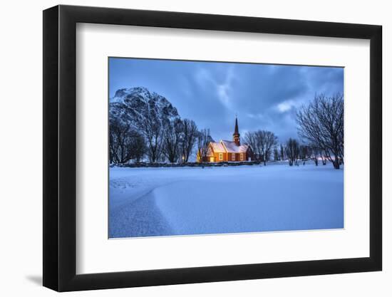 The illuminated church at dusk in the cold snowy landscape at Flakstad Lofoten Norway Europe-ClickAlps-Framed Photographic Print