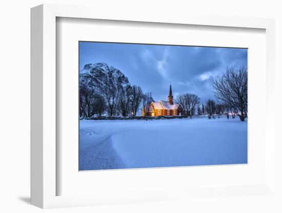 The illuminated church at dusk in the cold snowy landscape at Flakstad Lofoten Norway Europe-ClickAlps-Framed Photographic Print