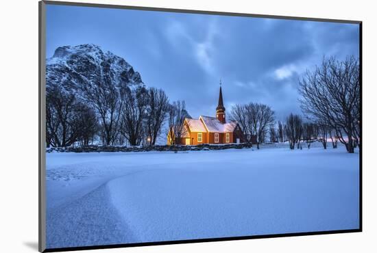 The illuminated church at dusk in the cold snowy landscape at Flakstad Lofoten Norway Europe-ClickAlps-Mounted Photographic Print