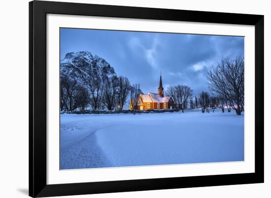 The illuminated church at dusk in the cold snowy landscape at Flakstad Lofoten Norway Europe-ClickAlps-Framed Photographic Print