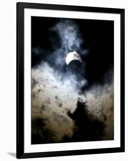 The Moon Partially Covers the Sun Behind the Clouds During a Partial Solar Eclipse-null-Framed Photographic Print